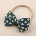 Détail d'un bandeau bébé avec nœud tricoté à pois bleu foncé et jaune sur fond beige - Nœud Tricoté à Pois Bleu et Jaune (#8)
