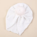 Close-up of white baby turban hat with twisted cable knit texture and top ball detail - White