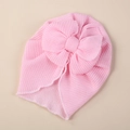 Pink knit baby turban hat with large double bow decoration and wavy edges on beige background - One Size / Bright Pink
