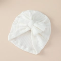 Detalle de turbante blanco para bebé con un gran lazo suave sobre un fondo de color neutro - Blanco