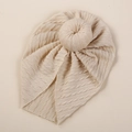 Detailed texture of beige knit baby turban hat with a stylish donut knot decoration - Off White