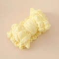 Détail du bandeau bébé jaune clair avec un grand nœud et une texture gaufrée seersucker - Beige