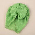 Close-up of grass green knitted baby turban hat with a large decorative bow detail - One Size / Verdant