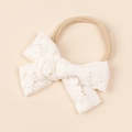 Vista dettagliata del fiocco in pizzo bianco morbido e della fascia elastica in nylon - 10x8cm / Bianco