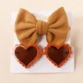 Detail of mustard yellow knit bow headband and orange heart sunglasses set on white card - Orange