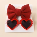 Detail view of red knitted bow headband and heart-shaped sunglasses set on display card - Red
