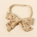 Dettaglio fascia per neonati con fiocco floreale in cotone e trama del tessuto morbido - Beige Floreale
