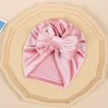 Detail of pink velvet baby turban with a large bow and soft pleated texture on a tray - Pink