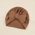 Detailed view of caramel brown baby turban hat with oversized knit bow on beige background - 17.5*18cm / Camel