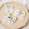 Detailed close-up of three floral bow hair clips in cream cotton on a stone tray - 11.5x10cm / Random Color