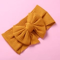 Ginger yellow knitted baby headband with a large textured bow on a pink background - Bow Ribbed Style / 17*9cm / Ginger Yellow