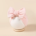 Détail d'un bandeau rose pour bébé avec un grand nœud sur un modèle en mousse blanc - 16*8.5cm / Rose