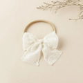 Detailansicht eines Baby-Stirnbands mit weißer Spitzenschleife und elastischem Nackengurt - 8.5x8.5cm / Weiße Kante