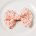 Primer plano de lazo de encaje rosa con bordado floral en un plato de cerámica blanca - Rosa