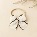 Vue détaillée du nœud en dentelle brodée sur un bandeau élastique pour bébé - 8.5x8.5cm / Naturel Avec Bord Noir