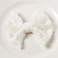 Close-up of white lace bow with delicate floral embroidery and scalloped edges - White