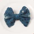 Detailed view of a navy blue lace butterfly hair clip with floral embroidery on ceramic tray - Blue