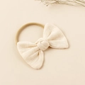 Detalle de una diadema con lazo de lino beige crema y textura de nailon elástico suave - Blanco Roto