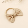 Detailed macro view of an oatmeal linen bow headband with stretchy nylon elastic band - Nude