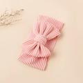 Détail du bandeau bébé en maille côtelée rose avec un grand nœud sur fond beige - Rose