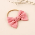 Pink waffle texture baby bow headband with high-stretch nylon band on minimalist background - Peach