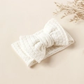 Detail of white waffle knit baby headband featuring a large soft bow on a beige background - 16x8.5cm / White