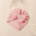 Detailed view of pink striped baby turban hat with a large bow on warm background - Pink