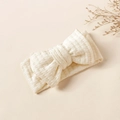 Detailed view of cream waffle knit baby headband with a large soft decorative bow - 16x8.5cm / Beige