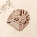 Detail der gestreiften Baby-Turban-Mütze mit großer Schleife auf neutralem Grund - Hellkhaki