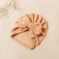 Detailed close-up of orange and white striped baby turban with large decorative bow - Orange