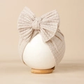 Détail d'un bonnet bébé beige en maille gaufrée avec un grand nœud décoratif - Abricot