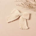 Dettaglio ravvicinato del fermaglio per capelli a fiocco in lana a maglia crema - Beige