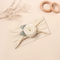 Detail eines Baby Stirnbands mit weißer Netzrose und Blättern auf Rippstrick - Gebrochenes Weiß