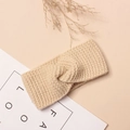 Gros plan d'un bandeau torsadé en maille épaisse crème sur fond rose poudré - 16*7cm / Abricot