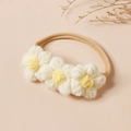 Détail de trois marguerites au crochet sur un bandeau en nylon souple pour bébé - Beige