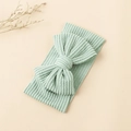 Bandeau bébé vert menthe en maille côtelée avec un grand nœud sur fond beige - Vert