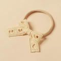 Detalle de lazo de encaje beige con patrones de corazones en diadema elástica para bebés - Blanco Roto