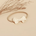Détail d'un bandeau souple pour bébé avec nœud en ruban blanc crème sur fond naturel - Blanc Cassé Avec Nœud Noir
