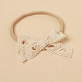 Close-up of baby lace headband featuring an intricate hollow heart pattern and soft nylon band - Ivory