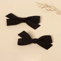 Macro detail of two solid black fabric bow hair clips on a minimalist beige background - Black