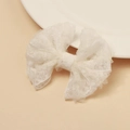 Dettaglio del fiocco in pizzo bianco con delicata trama a rete sul bordo di un piatto in ceramica - Bianco