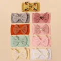 Pack of 9 baby nylon headbands with large lace bows and embroidery details on a beige background - Random Color