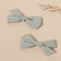 Detail of light blue-grey linen bow hair clips showing natural fabric texture on beige background - Bean Green