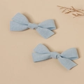 Detail of two light blue linen bow hair clips with textured fabric on a natural background - Light Blue