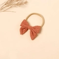 Detail view of brick red fabric bow headband with intricate floral hollow embroidery - Caramel Brick Red