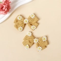 Detailed macro view of two ginger cotton hair clips with embroidered daisy patterns - 2 Pcs/Set / Yellow
