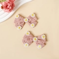 Détail de barrettes à nœuds en coton rose avec broderies de marguerites sur tissu doux - Rose Peau Clair