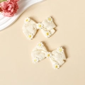 Gros plan de pinces à cheveux à nœud en coton blanc crème avec broderie marguerite - Blanc Cassé