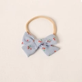 Détail d'un bandeau pour bébé en nylon souple avec nœud à carreaux et motif cerise - Bleu