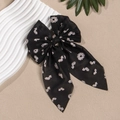 Detail eines schwarzen Haarschmucks mit Gänseblümchen-Druck und langen Bändern - Schwarz